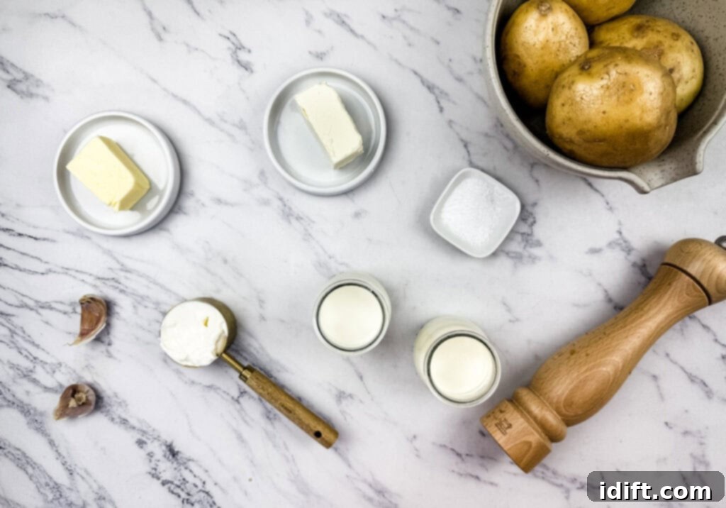 Mashed potato with cream cheese ingredients on a marble surface, including butter, cream cheese, sour cream, garlic, milk, salt, pepper, and a bowl of potatoes.