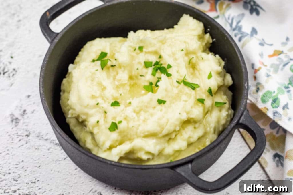 Rustic mashed potatoes served in a black pot, topped with melted butter and fresh parsley.