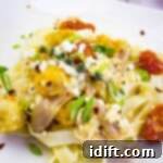 baked feta pasta on a square plate with tomatoes in the background