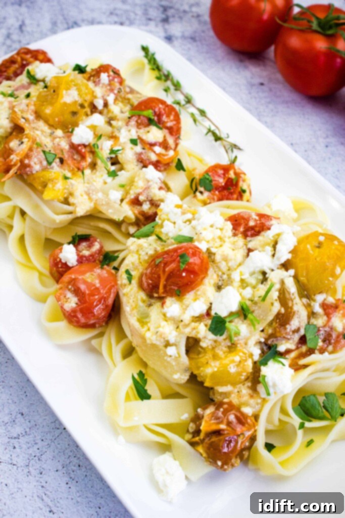 baked feta pasta on a square plate with tomatoes in the background