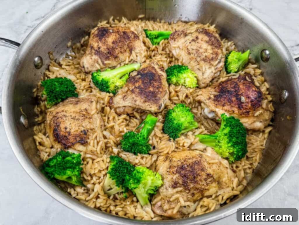 Skillet-cooked lemon chicken thighs with perfectly cooked orzo pasta and vibrant broccoli florets, creating a flavorful and wholesome one-pan meal, simmering under a lid.