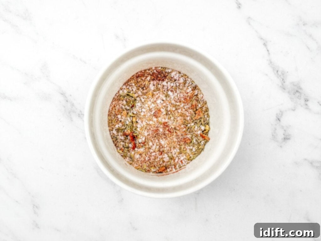 A white bowl containing a mix of various spices and herbs on a white marble surface.