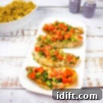 Pork chops with Tomato & Green Onion Relish on a white platter with couscous in the background