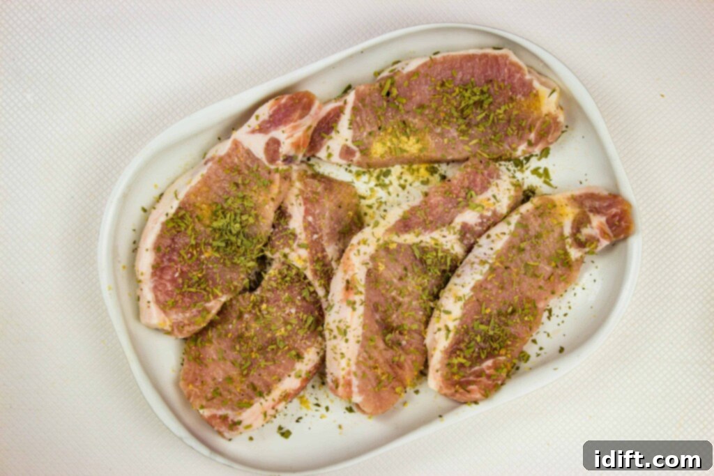 Boneless pork chops seasoned with salt, pepper, garlic powder and tarragon, ready for searing.