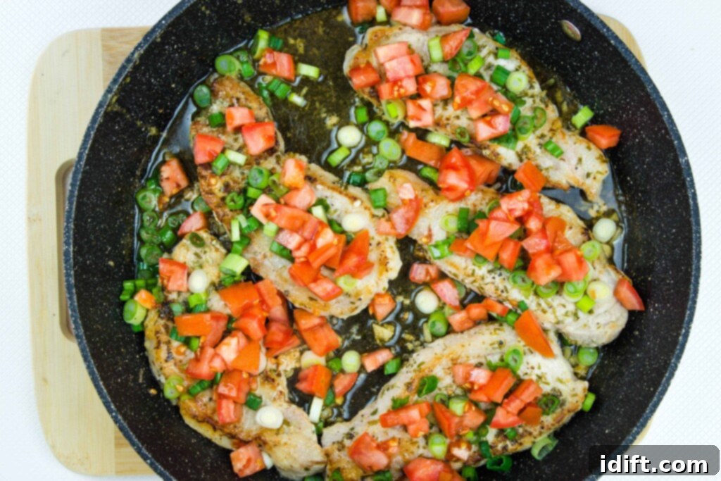 Cooked pork chops, beautifully topped with a fresh and colorful tomato and green onion relish, ready to be served.
