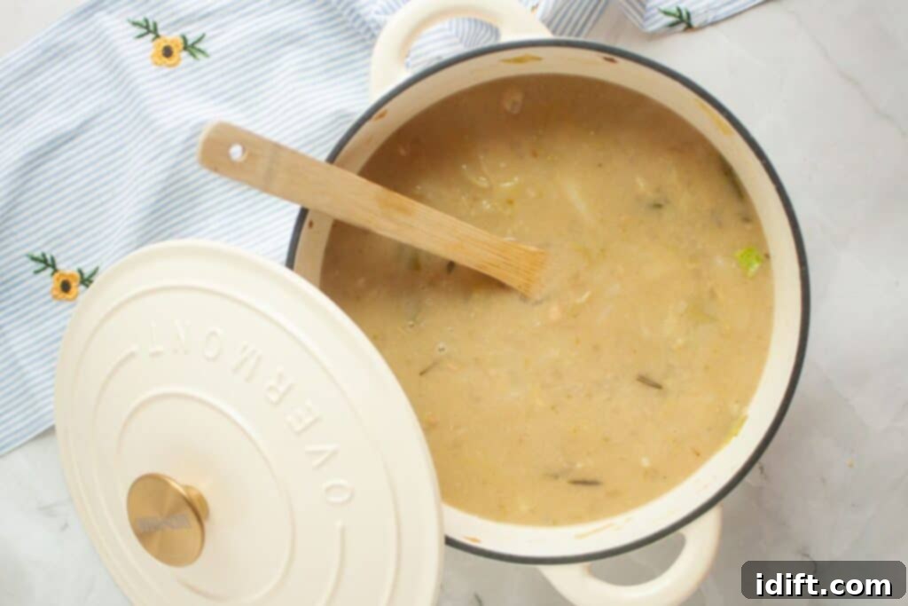 A inviting pot of vegetable soup, with a wooden spoon peeking out, sits on a pristine white surface. Beside it, a beautifully embroidered striped cloth adorned with delicate flowers adds a touch of charm and homeliness.