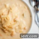A bowl of Cabbage and Bean Soup with chunks of cabbage and chickpeas, placed on a marble surface next to a spoon and a striped napkin.