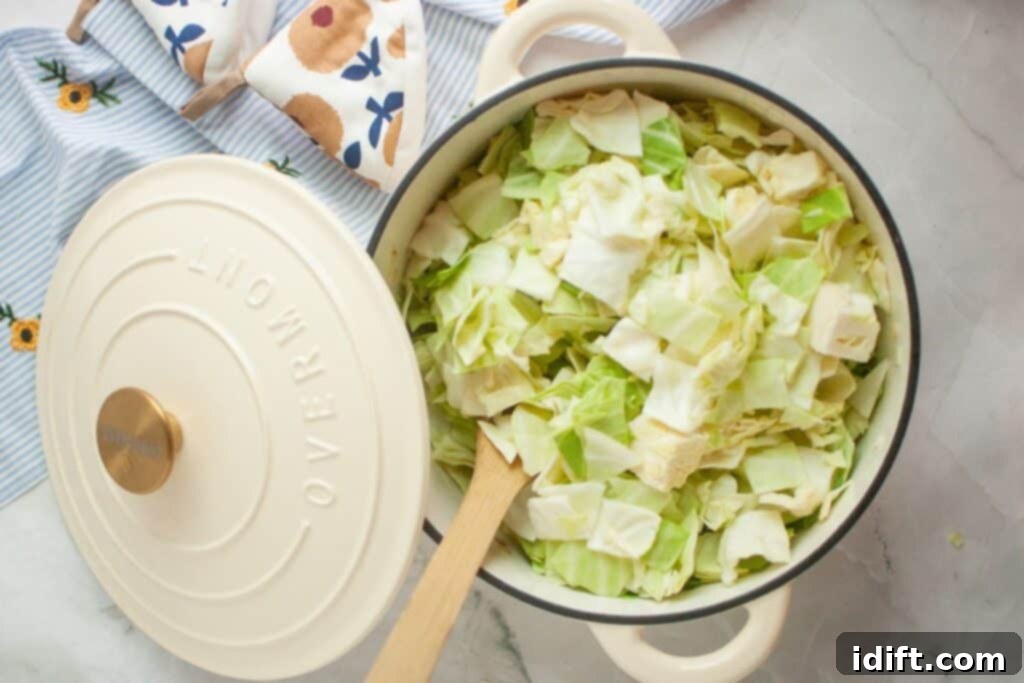 A pristine white pot, filled with freshly chopped cabbage, rests on a textured striped cloth. A wooden spoon, ready for stirring, is nestled within the vibrant greens.