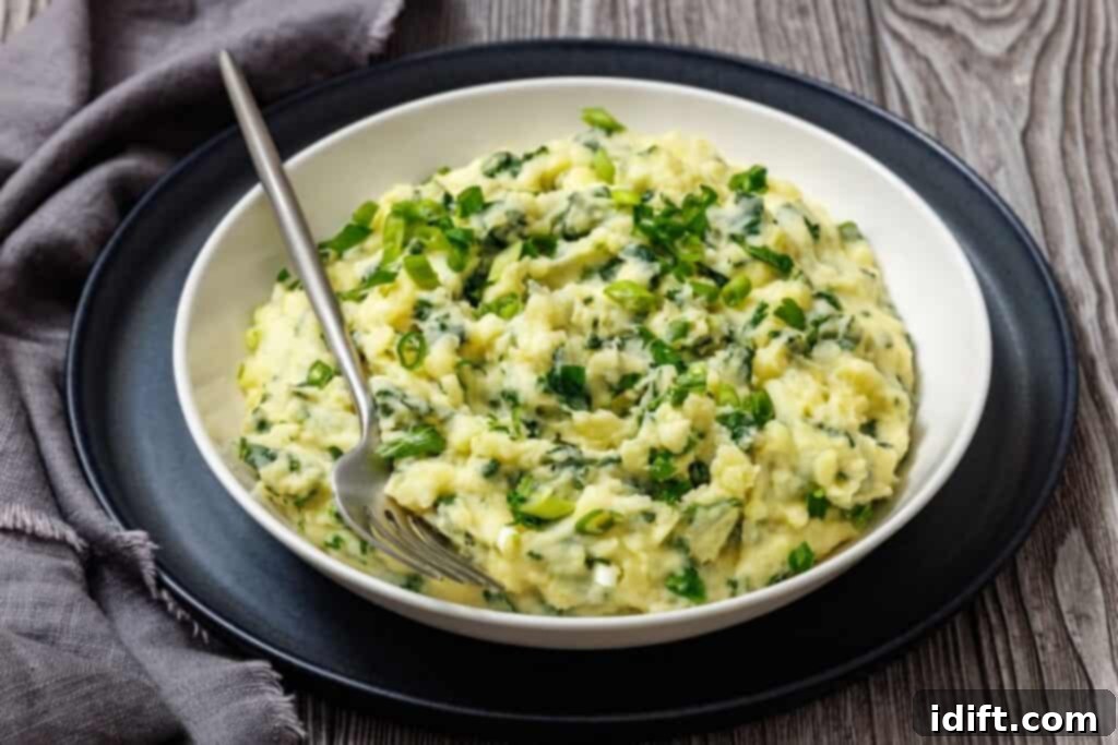 A bowl of Colcannon with Kale garnished with chopped green onions, with a fork resting inside.