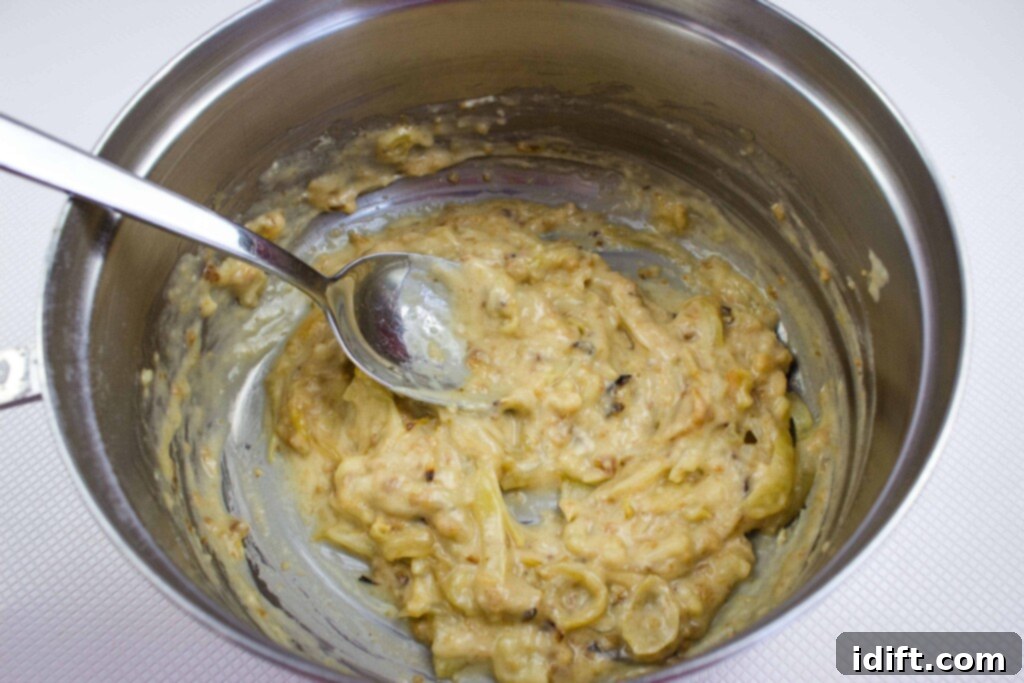 The process of making a thick paste with flour and rich drippings in a pot, demonstrating the start of a smooth gravy creation.