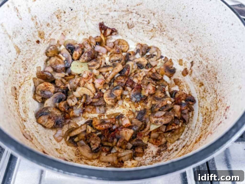 Hearty Beef Stroganoff Soup 8 Fragrant sautéed mushrooms and onions simmer together in a large, inviting pot on the stovetop, filling the kitchen with their delicious aroma.