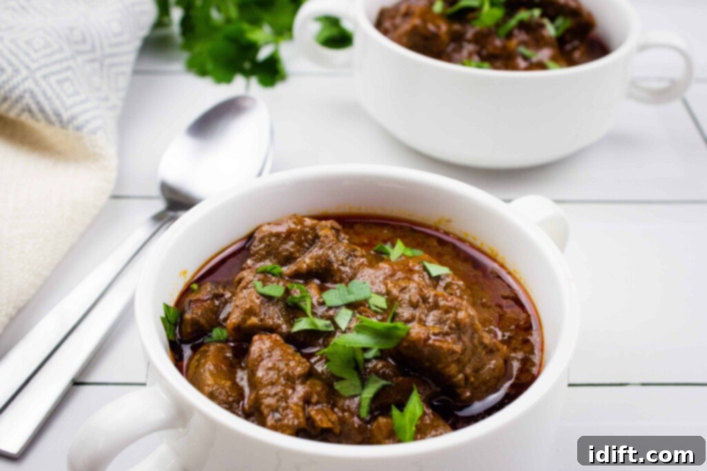 Hearty Hungarian Goulash 2 Authentic Hungarian Goulash in a pristine white bowl, garnished with fresh herbs, ready to be served.