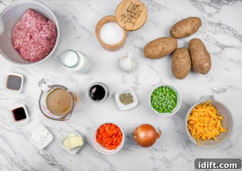 Ingredients for Shepherd’s Pie Baked Potatoes arranged on a marble surface, including ground meat, potatoes, onion, carrots, peas, butter, broth, cream, soy sauce, garlic, salt, pepper, cornstarch, and cheese.