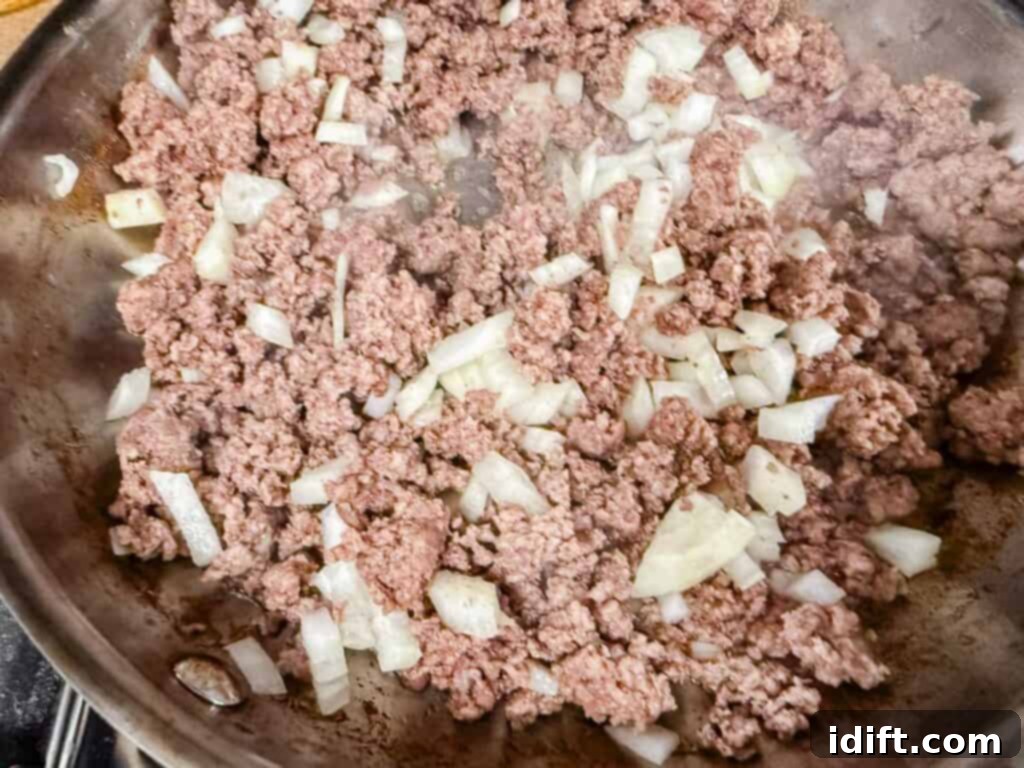 Ground meat and chopped onions cooking in a pan.