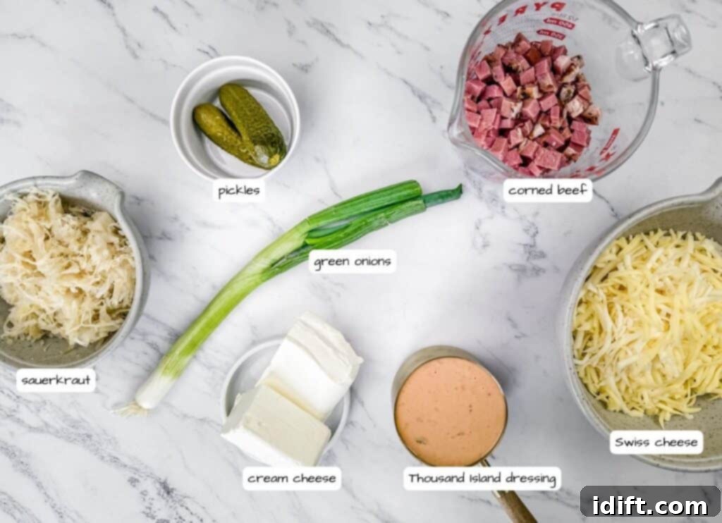 Golden Baked Reuben Dip 3 Ingredients for a Reuben dip arranged on a marble surface include sauerkraut, pickles, green onions, cream cheese, corned beef, Thousand Island dressing, and Swiss cheese.
