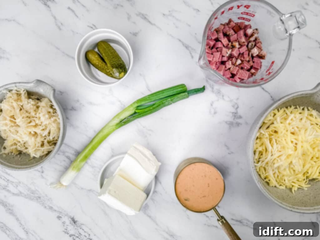Golden Baked Reuben Dip 4 Ingredients on a marble surface: sauerkraut, pickles, chopped meat in a measuring cup, shredded cheese, cream cheese, sliced green onion, and a cup of sauce.