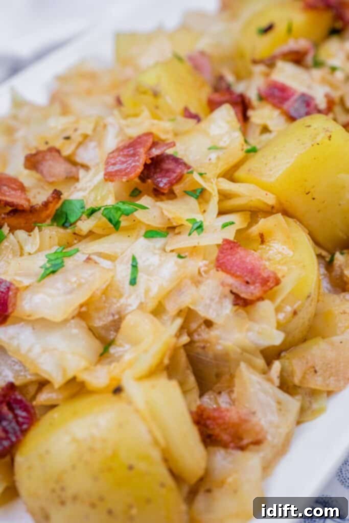 Savory sautéed Cabbage & Potatoes with Bacon, garnished with fresh parsley on a white serving dish.
