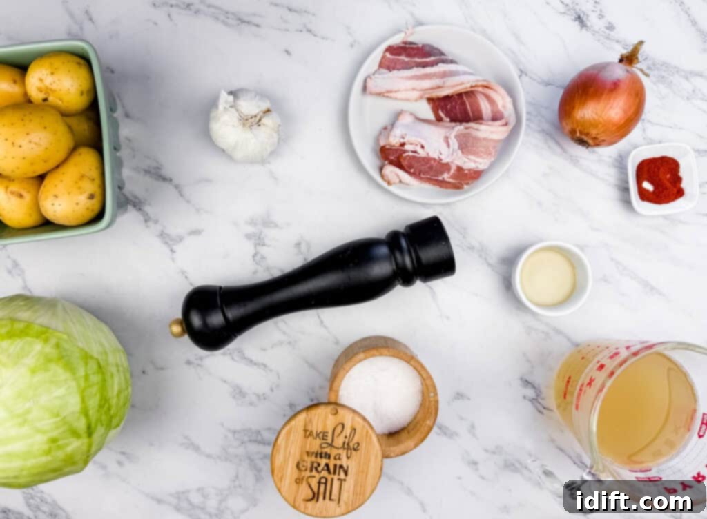 Ingredients for Cabbage & Potatoes with Bacon on a marble surface include potatoes, cabbage, garlic, bacon, onion, salt, pepper, smoked paprika, olive oil, and a measuring cup with liquid.