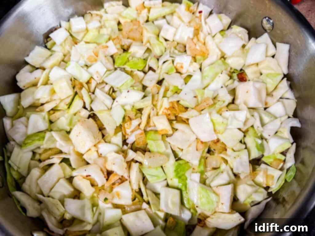 Chopped cabbage and onions cooking in a pan.