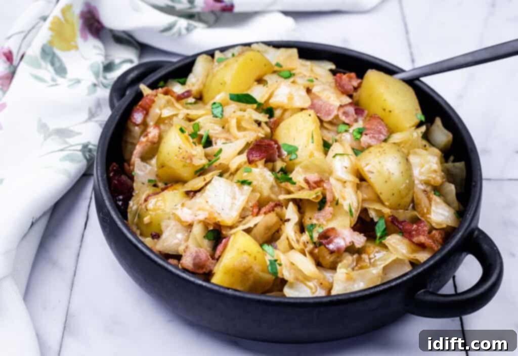 A black bowl filled with Cabbage & Potatoes with Bacon with a spoon on the side.
