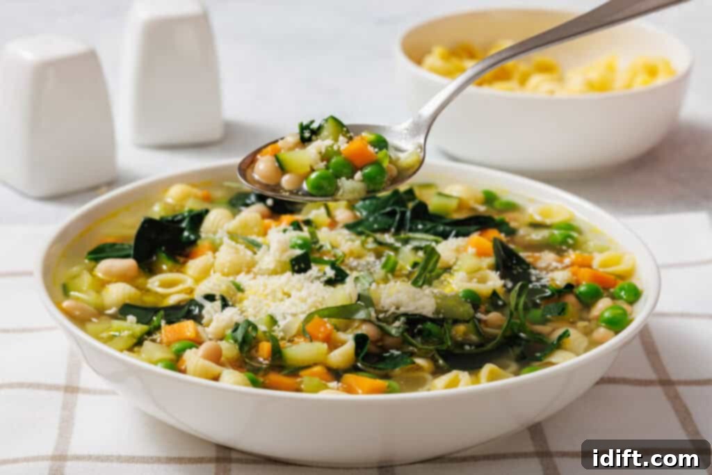 Vibrant Spring Minestrone 10 A bowl of Spring Minestrone with pasta shells, peas, carrots, beans, and greens. A spoon hovers above, holding a serving. Salt and pepper shakers in the background.