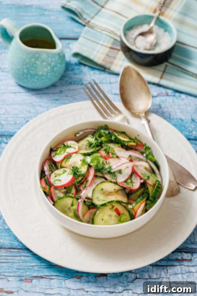 Bowl of Radish Salad with herbs on a white plate. Vintage fork and spoon on the side. Light blue wooden table background with a small jug and a napkin.