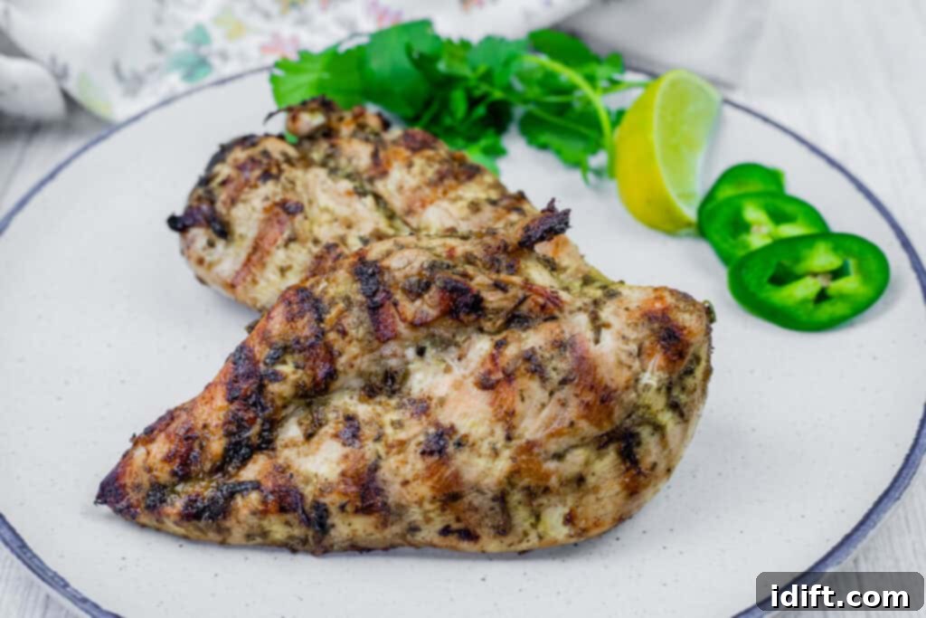 Grilled Lime Garlic Chicken on a white plate with cilantro and a slice of lemon on the side.