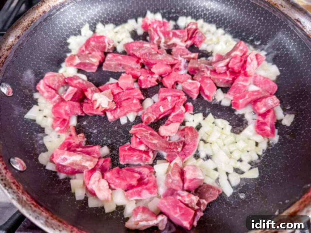 Steakhouse Fried Rice 6 seared onions with raw diced steak in a skillet.