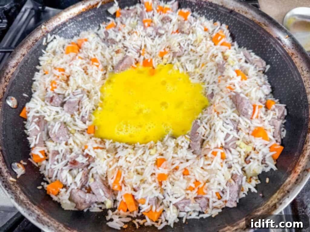 Steakhouse Fried Rice 8 seared rice with carrots and raw egg in the middle of a skillet pan.