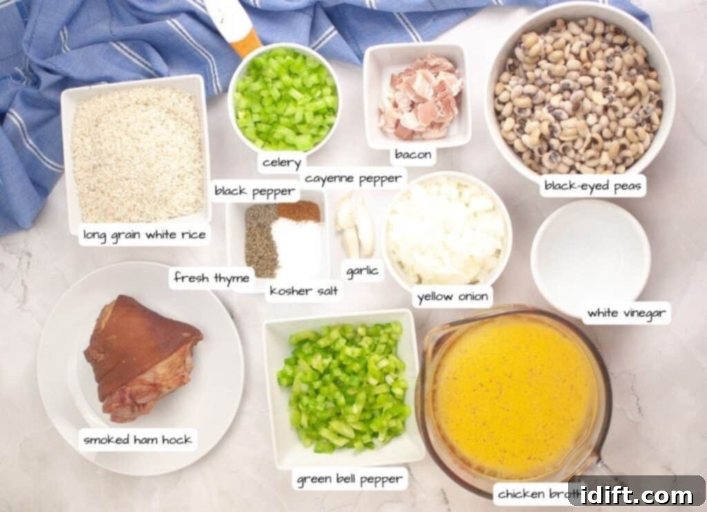Overhead view of labeled ingredients for a dish, including rice, celery, bacon, black-eyed peas, spices, onion, vinegar, ham hock, bell pepper, garlic, and chicken broth.