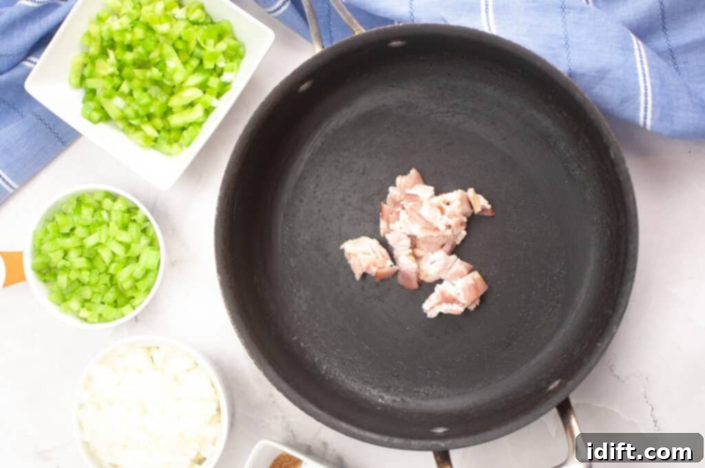Chopped bacon pieces in a skillet with bowls of chopped celery, green bell pepper, and onion on the side.