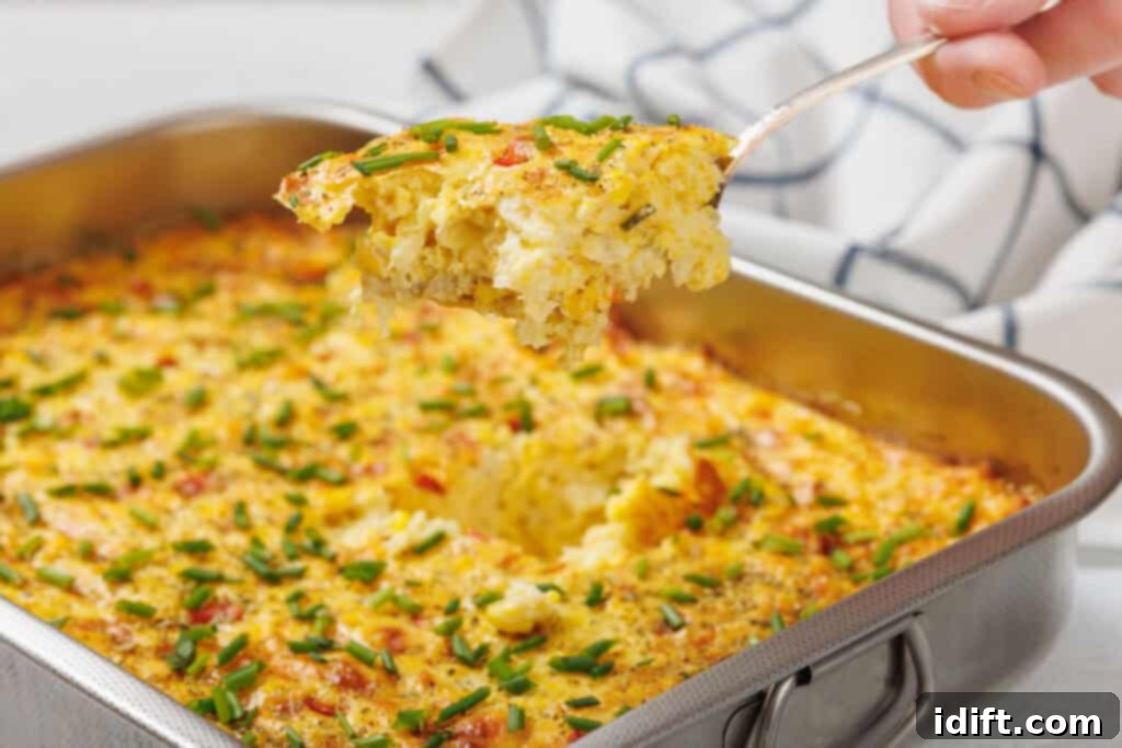 Creamy Golden Corn Bake 10 A serving of corn pudding casserole with chopped chives is lifted from a rectangular metal baking dish.
