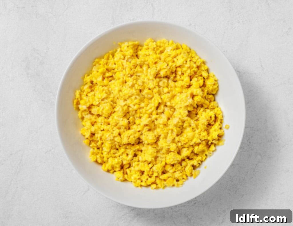 Creamy Golden Corn Bake 7 A white bowl filled with corn mixture sits on a light gray surface.
