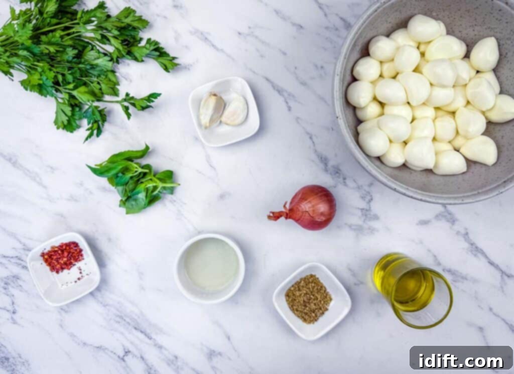 Flat lay of parsley, basil, garlic, shallot, red pepper flakes, vinegar, oregano, olive oil, and a bowl of peeled pearl onions on a marble surface.