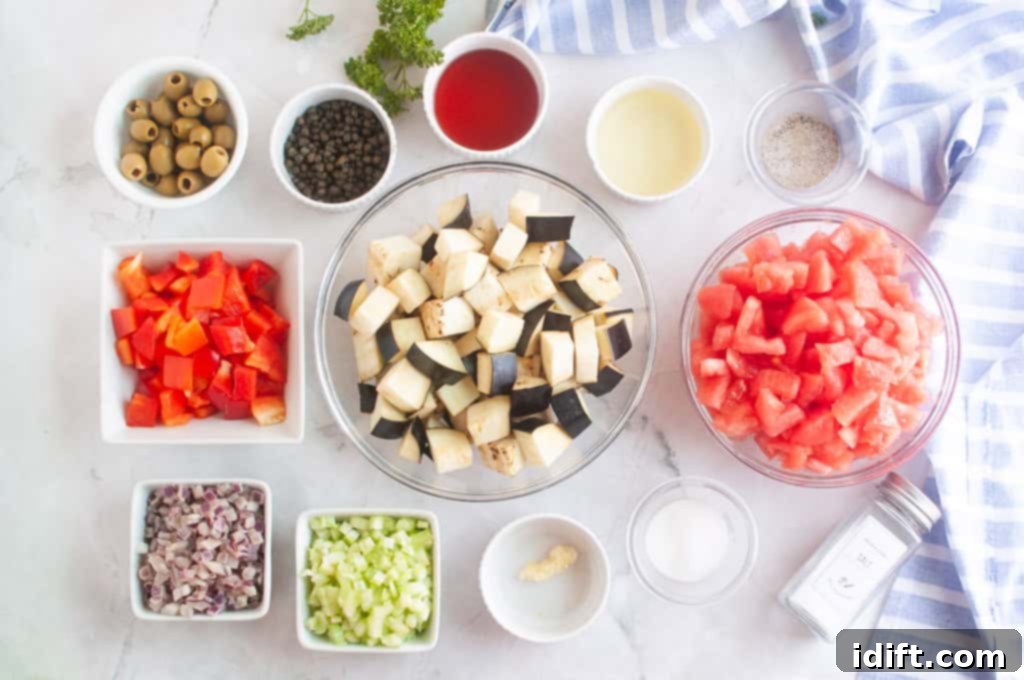 Chopped eggplant, tomatoes, red bell pepper, celery, shallots, garlic, olives, capers, and seasonings arranged in bowls on a white surface.