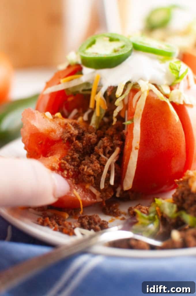 A beautifully arranged plate of Taco Stuffed Tomatoes, garnished with fresh herbs and a dollop of sour cream, ready to be enjoyed.