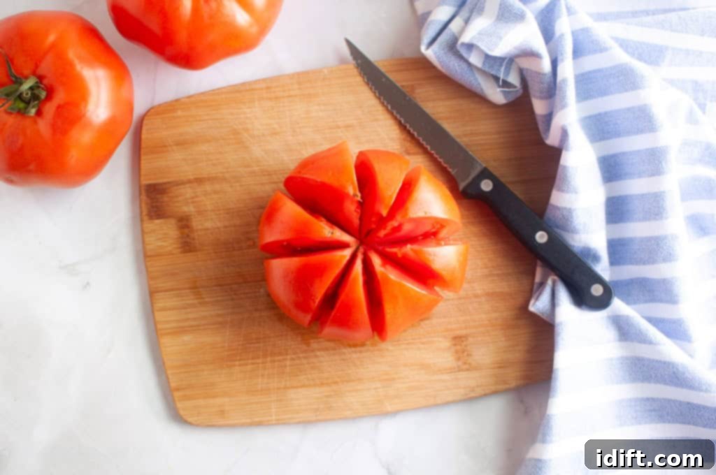 An overhead shot of a ripe tomato partially sliced into delicate wedges on a rustic wooden cutting board, alongside a sharp knife.