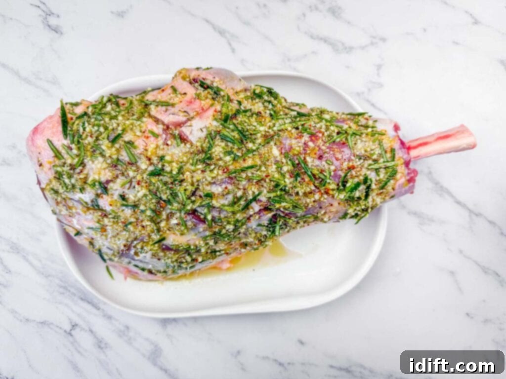 Aromatic Slow-Roasted Lamb Leg 8 Overhead shot of a raw leg of lamb on a white platter, meticulously coated in a vibrant green herb and garlic marinade, ready for resting.