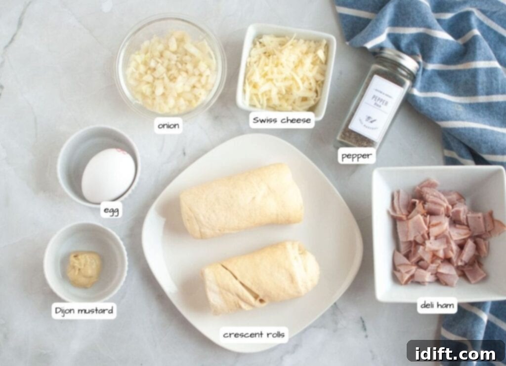 Fluffy Ham and Cheese Bites 4 Overhead shot of labeled ingredients for Ham and Cheese Puffs, including crescent rolls, deli ham, Swiss cheese, onion, egg, Dijon mustard, and pepper, all neatly arranged.