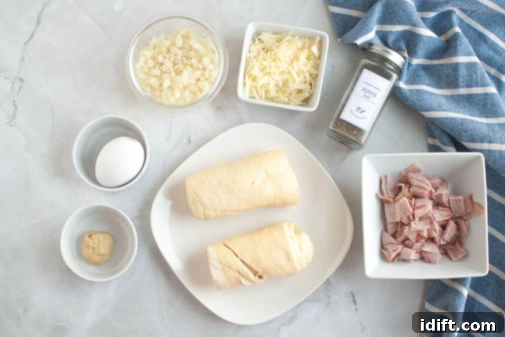 Fluffy Ham and Cheese Bites 5 Overhead shot of all ingredients for Ham & Cheese Puffs laid out: crescent dough, diced ham, shredded cheese, diced onion, an egg, Dijon mustard, and black pepper.