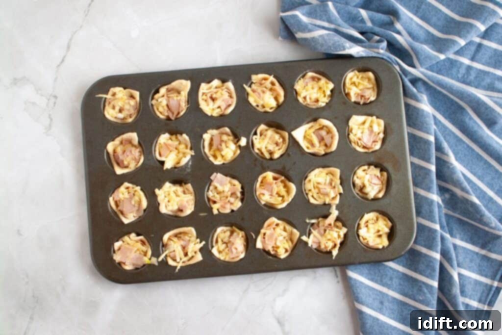 Fluffy Ham and Cheese Bites 9 Overhead shot of a mini muffin tin, with each pastry cup filled with a generous spoonful of the ham and cheese mixture, ready for baking.