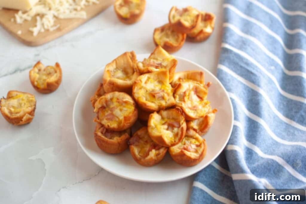 Fluffy Ham and Cheese Bites 10 A white plate generously piled with small, golden-brown ham and cheese puffs, showcasing their perfect baked texture.