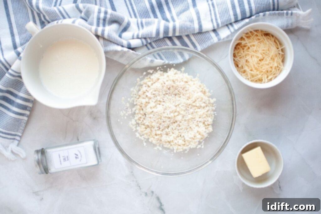 A bowl of breadcrumbs, grated cheese, butter, cream, and a jar of salt on a marble surface with a striped cloth.