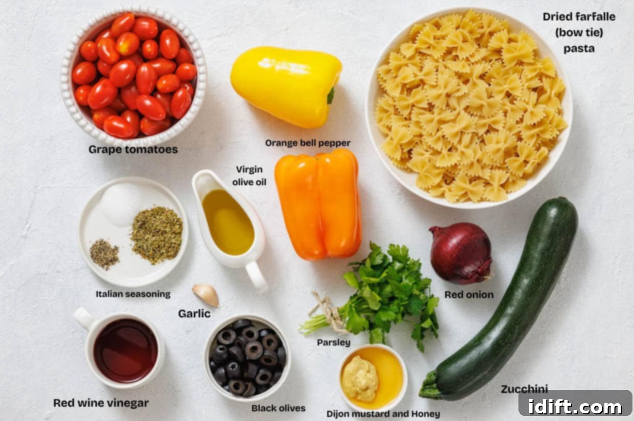 Overhead view of ingredients for a pasta salad, including farfalle, grape tomatoes, bell peppers, red onion, zucchini, olives, parsley, garlic, seasonings, olive oil, vinegar, and mustard.