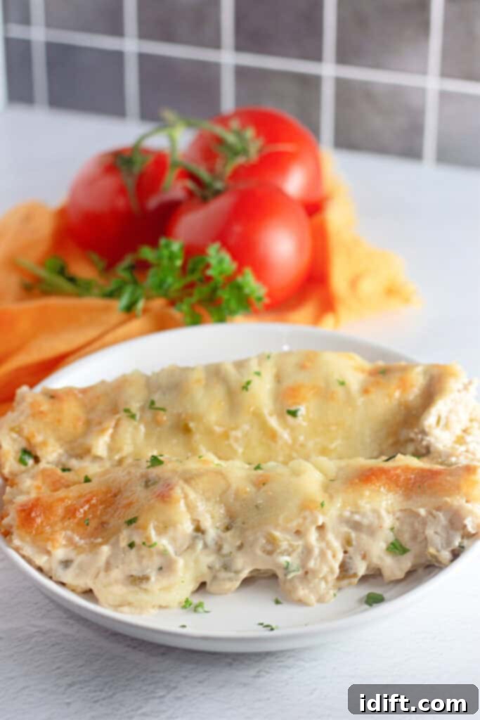 Velvety Chicken Enchiladas 2 A plate of White Chicken Enchiladas, garnished with fresh parsley, with vibrant tomatoes and herbs in the soft-focus background.