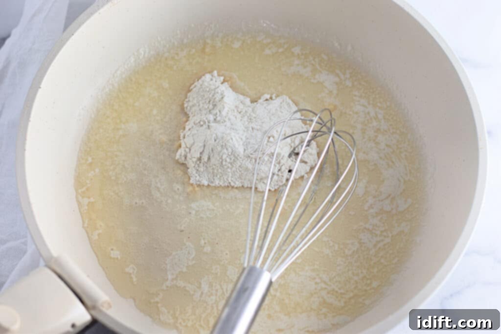 Velvety Chicken Enchiladas 6 A silicone whisk expertly stirring all-purpose flour into melted butter in a light-colored nonstick pan, creating a smooth roux.