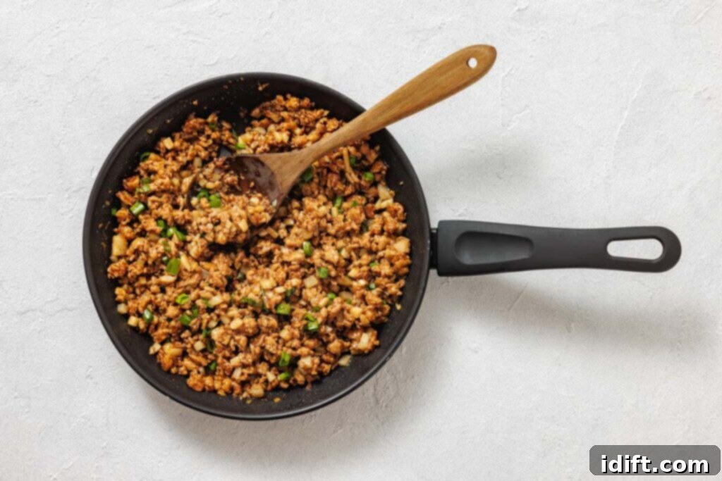A pan filled with food and a wooden spoon.