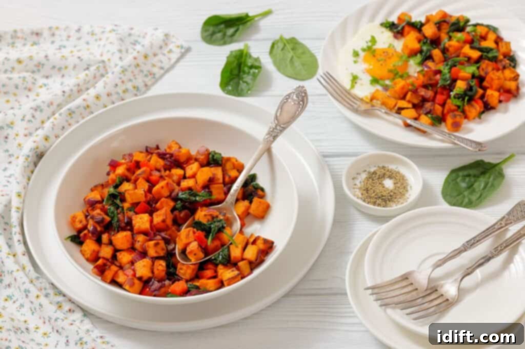 Golden Sweet Potato and Spinach Hash 3 A bowl of sweet potato hash with spinach and red onions, served with a side plate, fork, and a dish of ground pepper on a white table. The hash is artfully arranged with a golden-yolked egg on top, garnished with fresh green herbs.