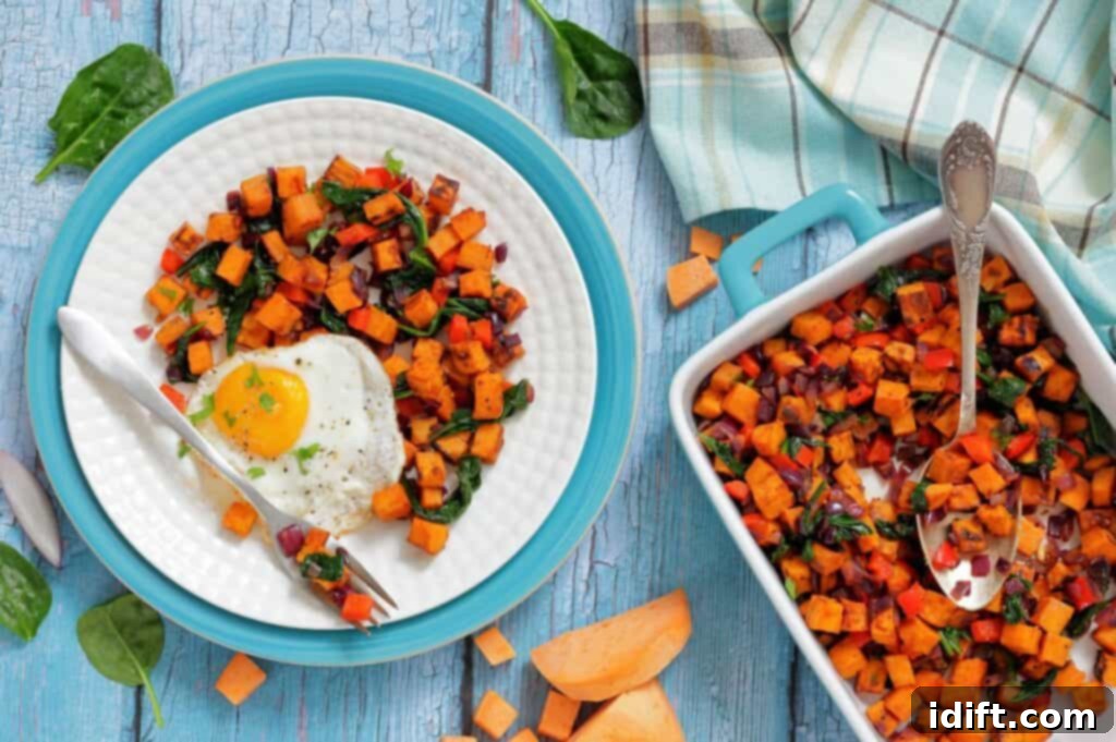 Golden Sweet Potato and Spinach Hash 5 A plate with a fried egg and a serving of sweet potato hash next to a baking dish filled with more hash on a blue wooden table with a cloth napkin. The hash is garnished with fresh herbs, and the egg has a perfectly runny yolk.
