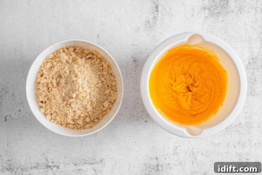 Two white bowls on a light surface: one filled with crumbled dry mixture, the other containing smooth orange batter.